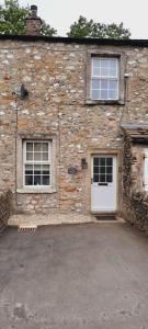 un edificio de piedra con 2 puertas blancas y 2 ventanas en Appleyard Cottage - Yorkshire Dales, en Hellifield