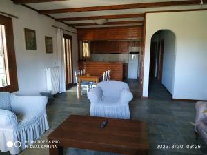 a living room with white chairs and a table at House By The Sea in Artemida
