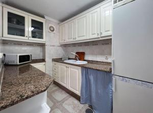 una cocina con armarios blancos y fregadero en Apartamento en El Puerto de Santa María, en El Puerto de Santa María