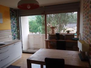 uma cozinha com uma mesa e uma grande janela em Appartement avec balcon : Le Serenity em Turckheim