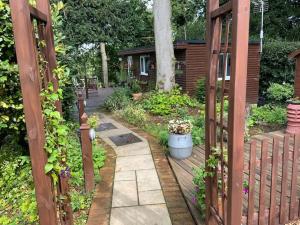 un jardín con una valla de madera y una pasarela en Eve’s Contemporary Cabin in Kent Woodland Setting, en Kent