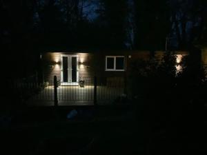 una casa con una puerta blanca por la noche en Eve’s Contemporary Cabin in Kent Woodland Setting, en Kent