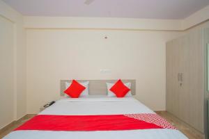 a bedroom with a white bed with red pillows at PRIDE MANYATA in Bangalore