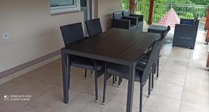 uma mesa de jantar preta com cadeiras pretas em Guest House Vila Aleksa-apartman em Bogutovac