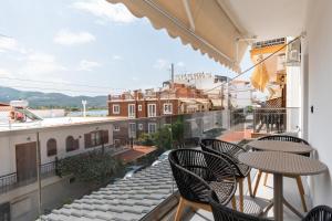 a balcony with tables and chairs and a view of a city at SithoniaRS Luxury 1st Floor Apartment With SeaView in Neos Marmaras