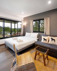 a bedroom with a bed and a chair and windows at Naramountainkhaoyai 04 in Ban Tha Chang