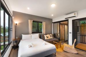 a bedroom with a white bed and a living room at Naramountainkhaoyai 04 in Ban Tha Chang