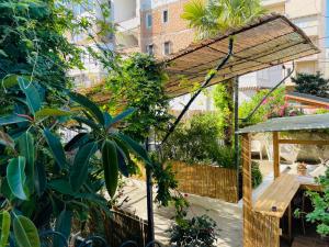 a garden with a wooden pergola and a wooden table at Adriatic Hostel Vlora in Vlorë