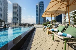 a swimming pool with chairs and an umbrella on a building at Alberto by Isrotel Design in Tel Aviv