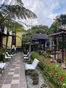 um jardim com cadeiras brancas e flores e um edifício em THE HIGHLANDS VILLA em Tanah Rata