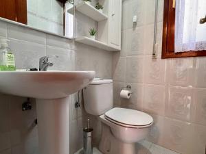 Łazienka z białą toaletą i umywalką w obiekcie Casa adosada en Argoños w mieście Argoños