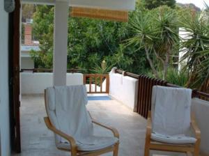 two white chairs sitting on a porch with trees at Villa 2M a 50 metri dal mare in San Vito lo Capo