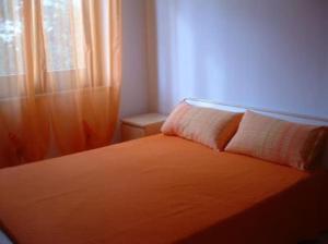 a bedroom with an orange bed with a window at Villa 2M a 50 metri dal mare in San Vito lo Capo