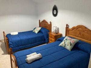 1 Schlafzimmer mit 2 Betten mit blauer Bettwäsche und einem Spiegel in der Unterkunft Casa Cueva Rural Estación de Guadix in Guadix