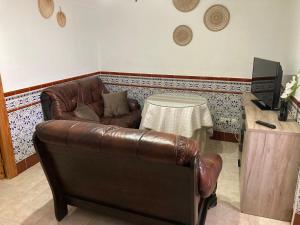- un salon avec un canapé en cuir et une table dans l'établissement Casa Cueva Rural Estación de Guadix, à Guadix