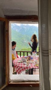 twee personen aan een tafel met uitzicht vanuit een raam bij Bujtina Carku in Theth