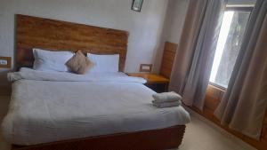 une chambre avec un lit avec une tête de lit en bois et une fenêtre dans l'établissement Corbett Call Resort, à Rāmnagar
