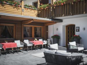 eine Terrasse mit Tischen und Stühlen sowie einen Balkon in der Unterkunft Hotel Brötz in Rasùn di Sotto
