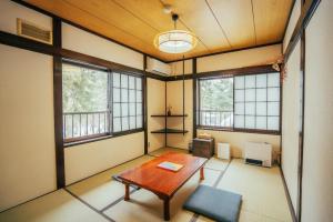 ein leeres Zimmer mit einem Tisch und einigen Fenstern in der Unterkunft LAMP Nojiriko in Shinano