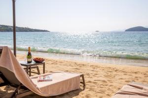 uma cadeira e uma mesa numa praia com uma garrafa de vinho em Villa Mediterrane Hotel em Iraklitsa