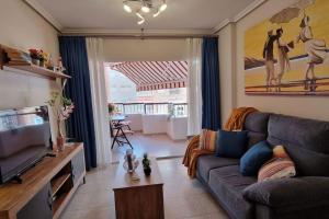 un salon avec un canapé et une télévision dans l'établissement Jardin playa del cura apartment, à Torrevieja