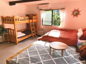 ein Schlafzimmer mit einem Bett, Etagenbetten und einem Tisch in der Unterkunft LAMP Nojiriko in Shinano