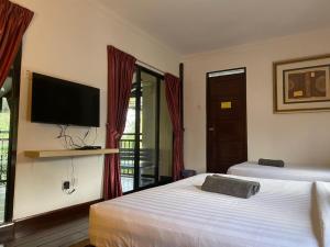 a bedroom with two beds and a flat screen tv at Cahaya Villa in Tanah Rata