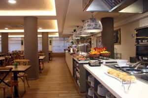 a large kitchen with tables and chairs in a restaurant at Hotel Metropol in Lloret de Mar