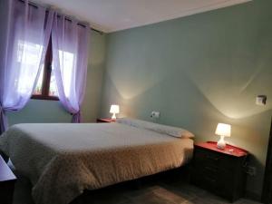 1 dormitorio con 1 cama con cortinas moradas y 2 lámparas en Loft en planta baja en Ciudad Rodrigo en Ciudad Rodrigo