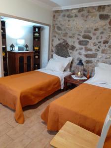 two beds in a room with a stone wall at Stone Clock's House in Nafpaktos