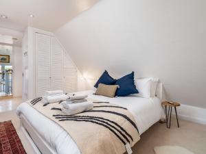 a white bedroom with a large bed with blue pillows at Pass the Keys The Sculptors Cottage in Aylesbury