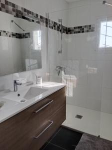 y baño blanco con lavabo y ducha. en Location maison à l'Epine sur Île de Noirmoutier, en LʼÉpine