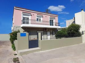 a pink house with a gate and a fence at Tranquility Base in Neapoli Voion