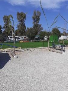 un parc avec une aire de jeux avec un banc et une balançoire dans l'établissement Bungalows Park Albufera, à El Saler