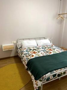 a bed with a green comforter in a room at Apartamento Solpor in Vilagarcia de Arousa