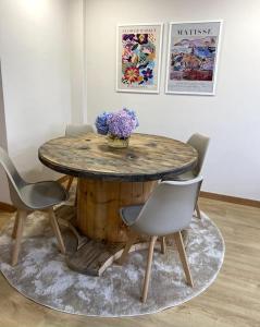 a wooden table with chairs and a table with flowers on it at Apartamento Solpor in Vilagarcia de Arousa
