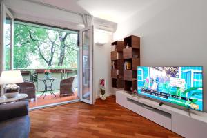 - un salon avec une télévision et une porte coulissante en verre dans l'établissement MiCo GARDEN VIEW CITYLIFE EXECUTIVE APARTMENT, à Milan