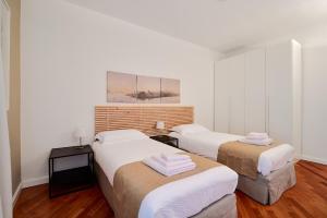 2 letti in una camera con pareti bianche e pavimenti in legno di MiCo GARDEN VIEW CITYLIFE EXECUTIVE APARTMENT a Milano