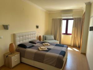 a bedroom with a bed and a chair and a window at Ericeira Sea&Sun Apartment 3 in Ericeira