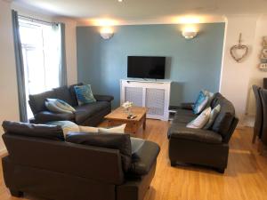 a living room with two couches and a tv at Waves in Saint Columb Major