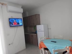 een keuken met een tafel en een tv aan de muur bij Appartamento per vacanze estive in Vlorë