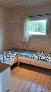 two beds in a log cabin with a window at Domki Wysokie Trawy Zdory in Pisz