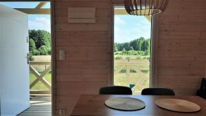 ein Esszimmer mit einem Tisch und einem großen Fenster in der Unterkunft Domki Wysokie Trawy Zdory in Pisz