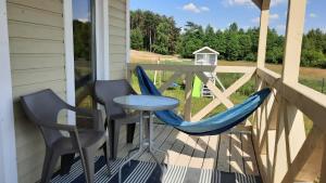 a porch with two chairs and a table and a small table at Domki Wysokie Trawy Zdory in Pisz