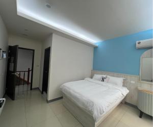 ein Schlafzimmer mit einem weißen Bett und einer blauen Wand in der Unterkunft 易宿輕旅民宿Easy Go B&B in Huxi