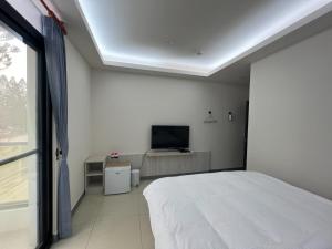 a bedroom with a bed and a flat screen tv at 易宿輕旅民宿Easy Go B&B in Huxi