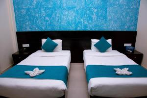 2 camas en una habitación con almohadas azules y blancas en Tuki Resort en Pokhara