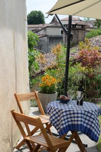 een tafel met 2 stoelen en een parasol op een patio bij La Maison du Tourniquet in Aubeterre-sur-Dronne