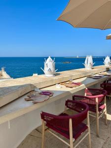 a table with chairs and an umbrella and the ocean at I Bastioni San Domenico - Boutique Hotel in Gallipoli