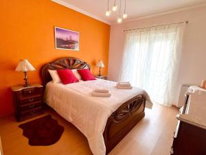 um quarto com uma cama grande e paredes cor-de-laranja em Appartement T2 avec vue panoramique sur la côte em Atouguia da Baleia